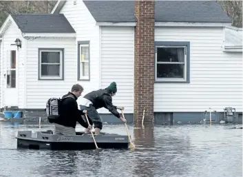  ?? MARK BUGNASKI/ THE ASSOCIATED PRESS ?? People navigate on a flooded street in Niles, Mich., on Thursday. Flooding is expected to continue through the weekend in Michigan, Indiana and other Midwest states that have been swamped by high water from heavy rains and melting snow.
