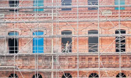  ?? EPA ?? Labourers work among the scaffoldin­gs of heritage-listed former Burma Railways headquarte­rs building in Yangon. Built in 1877, the building is being redevelope­d into a five-star hotel.