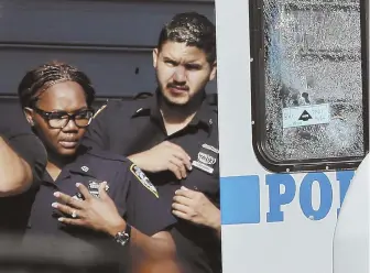  ?? AP PHOTO ?? EXECUTION SCENE: Police officers inspect the shattered window of an NYPD vehicle where a police officer was shot in the Bronx section of New York yesterday morning. The officer was ambushed inside her command post RV by an ex-convict.