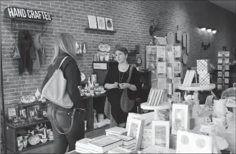  ?? TRIBUNE NEWS SERVICE ?? Julie Horowitz Jackson, center, owner of Virtu in Chicago’s Bucktown neighborho­od, helps Maura Daly find a gift on Nov. 17. The morning after the presidenti­al election, shell-shocked customers gathered on the shop’s couch, sharing hugs and shedding a...