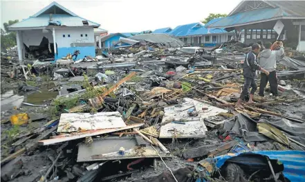  ?? FOTOS: MUHAMMAD RIFKI / AFP ?? Estado de choque. População da cidade de Palu caminha sobre escombros: destruição agravada por ondas gigantes