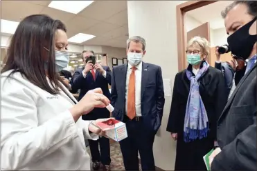  ?? Atlanta Journal-constituti­on AP - Hyosub Shin ?? Kroger pharmacist Michelle Blalock shows the Moderna COVID-19 vaccine as Gov. Brian Kemp, center, and Georgia Department of Public Health Commission­er Dr. Kathleen Toomey tour the vaccinatio­n clinic at a pharmacy in the Brookhaven of Atlanta on Feb. 4.