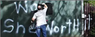  ??  ?? Cover-up: A workman paints over the offensive words in Worsley yesterday