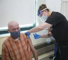  ?? NICOLAuS CzARnECkI / hERALD ?? WARDING OFF THE VIRUS: Pine Street Inn resident George Thomas gets the first COVID-19 vaccinatio­n from registered nurse Jessica Pasteris on Friday at the Pine Street Inn.