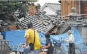  ?? Jiji Press / Getty Images ?? People pause to look at a house in Japan’s Ibaraki City, north of Osaka, that collapsed during a magnitude 6.1 earthquake.