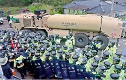  ??  ?? Protesters and police stand by as trailers carrying the THAAD missile defence equipment enter a deployment site in Seongju on Wednesday.