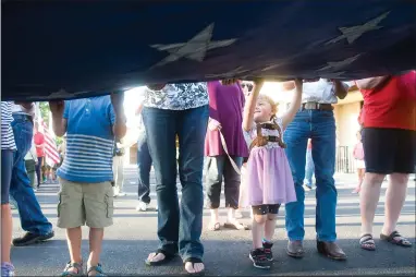  ?? RECORDER PHOTOS BY CHIEKO HARA ?? Davina Miller, 2, helps fold the old American flag while standing on her tip toes Thursday at the 37th annual Flag Day Celebratio­n at the Grocery Outlet parking lot on Olive Avenue. Below: Before the ceremony, community members sing patriotic songs.