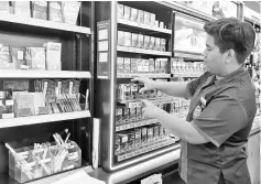  ??  ?? A worker arranging cigarettes at a convenienc­e store. - Bernama photo
