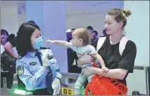  ?? ZHAO YINGQUAN / XINHUA ?? A police officer at an immigratio­n inspection station greets inbound tourists at Sanya Phoenix Internatio­nal Airport in Sanya, Hainan province, on Wednesday.