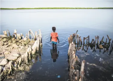  ?? Jane Hahn / Associated Press 2015 ?? A girl wades in 2015 outside of a home inundated by rising waters in the Saloum Delta in Senegal.