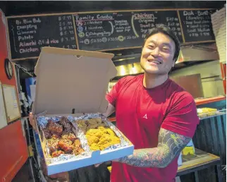  ?? TIM KROCHAK • FILE ?? Joungmin Kim, owner of Backoos Korean To Go Food, holds up an order of Half and Half Chicken in his Bedford Hwy establishm­ent in 2018.
