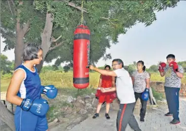  ?? BURHAAN KINU/HT PHOTO ?? Manju Rani’s coach Saheb Singh Narwal is seen with young boxers at a practice area, in Rohtak, Haryana on Sunday.