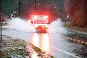  ?? The Sentinel-Record/Grace Brown ?? PUSHING THROUGH: A LifeNet ambulance runs with lights and sirens through partially flooded roadways on Park Avenue.