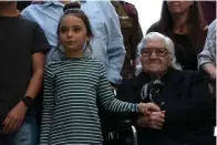  ?? Associated Press ?? ■ Melpomeni Dina holds the hand of an Israeli girl Sunday during a reunion at the Yad Vashem Holocaust memorial in Jerusalem. Dina, a 92-year-old Greek woman who rescued a Jewish family during the Holocaust has been reunited with two of the people she saved and dozens of their family members.