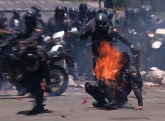  ?? PHOTO AFP ?? Un policier vient en aide à un collègue atteint par un cocktail Molotov qu’ont lancé des manifestan­ts opposés à l’élection d’une Assemblée constituan­te, dimanche. Depuis quatre mois, plus de 120 personnes ont péri au Venezuela.