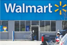  ?? AP FILE PHOTO/NAM Y. HUH ?? A woman pushes a shopping cart to enter a Walmart in Rolling Meadows, Ill.