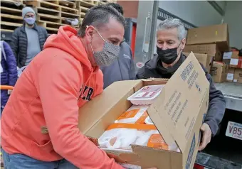  ?? COurtESy LOVIn’ SPOOnFuLS ?? ‘RATION IT OUT’: Paul Garino, left, gets a box of food from Jethro Caldira, both of Grace Food Pantry in Everett, as Lovin’ Spoonfuls makes a milestone delivery of 20 millionth pound to food pantries.