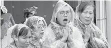  ??  ?? Volunteers pray for earthquake victims during a search operation at a collapsed apartment building in eastern Taiwan.