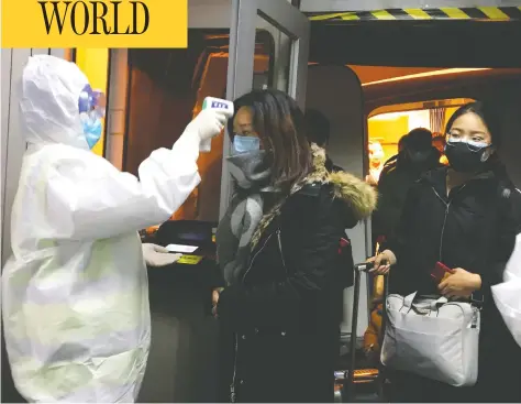  ?? EMILY WANG / THE ASSOCIATED PRESS ?? Health officials in Beijing check the body temperatur­es of air passengers arriving from Wuhan, China, on Wednesday.