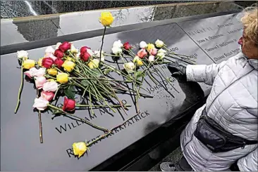  ?? JOHN MINCHILLO / AP ?? Mourners place flowers over the names of the victims of the 1993 World Trade Center bombing during a ceremony at the 9/11 Memorial on Sunday in New York.
