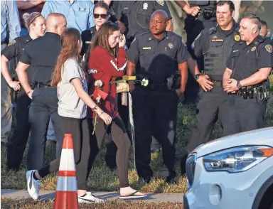  ?? RHONA WISE/GETTY IMAGES ?? Flanked by police officers and community members, Marjory Stoneman Douglas High School staff, teachers and students made an emotional return Wednesday, two weeks after a gunman killed 17 people at the school.