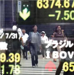  ??  ?? TOKYO: People are reflected on an electronic stock indicator of a securities firm in Tokyo yesterday. —AP
