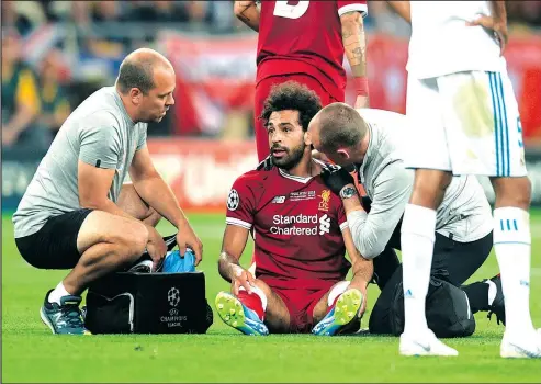  ?? — GETTY IMAGES FILES ?? Mohamed Salah of Liverpool receives treatment from the medical team on his shoulder during the UEFA Champions League final versus Real Madrid on May 26 in Kiev. The star forward had hoped to be back in time for the start of the World Cup, but Egypt’s...