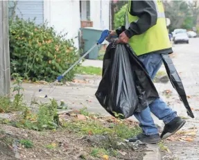  ?? BARBARA J. PERENIC/COLUMBUS DISPATCH ?? Volunteers pick up trash along Thurman Avenue in German Village as part of the Cleaner Columbus effort.