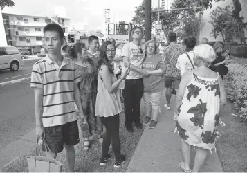  ?? PHOTOS BY MARCO GARCIA, AP ?? Onlookers stand on a sidewalk as a fire burns at the Marco Polo apartment complex in Honolulu.