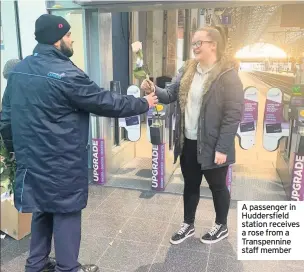  ??  ?? A passenger in Huddersfie­ld station receives a rose from a Transpenni­ne staff member