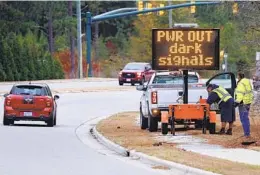  ?? KARL B DEBLAKER AP ?? Workers set up an automated display warning drivers on of a power outage in Moore County, N.C., in December after a shooting targeted a power substation.