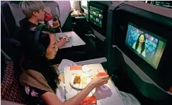  ?? AFP ?? iNAuGurAl luNch: diners watch movies while dining during the inaugural lunch onboard a Singapore Airlines plane at changi internatio­nal Airport. —