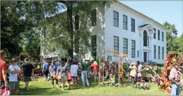  ?? John Popham / Rome News-Tribune ?? The tin artwork created by Argelia Gonzalez draws a crowd at the Cave Spring Art Festival on Saturday. Proceeds from the festival go to the upkeep of historic buildings such as the Hearn Academy building shown in the background.