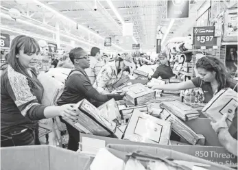  ?? GUNNAR RATHBUN, INVISION FOR WALMART ?? Customers sift through merchandis­e at a Walmart Black Friday event last year in Rogers, Ark.