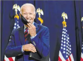  ?? Carolyn Kaster The Associated Press ?? Democratic presidenti­al candidate Joe Biden puts on his face mask Friday after speaking to media in Wilmington, Del.