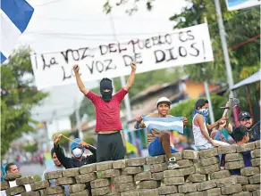  ?? ?? Jóvenes posan debajo de un cartel que aboga por la libertad religiosa en el régimen del presidente de Nicaragua, Daniel Ortega, durante las manifestac­iones ocurridas en 2018 en aquel país./