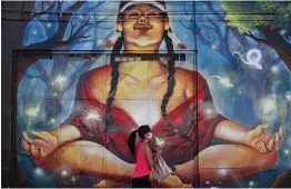  ?? — AP ?? A pedestrian walks past a mural of a Mapuche woman in Santiago, Chile, on Tuesday.