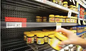  ?? — AP ?? Settling for the lesser: A customer taking a jar of Vegemite from next to an empty shelve where Marmite should be stocked in a supermarke­t in Auckland.