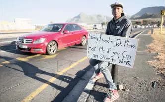  ?? EPA ?? AN UNEMPLOYED South African man holds a self-made advertisin­g board offering his services at a traffic intersecti­on in Cape Town.