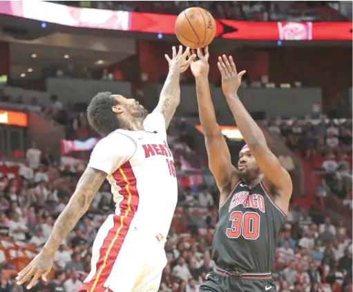  ?? JOEL AUERBACH/ AP ?? Bulls forward Noah Vonleh, who started and had 14 points and 13 rebounds, shoots over Heat forward James Johnson in the first half Thursday night.