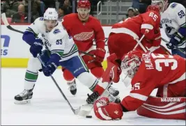  ?? The Associated Press ?? Detroit Red Wings goaltender Jimmy Howard reaches to cover the puck as Bo Horvat (53) of the Vancouver Canucks looks for a rebound during Tuesday’s game in Detroit.