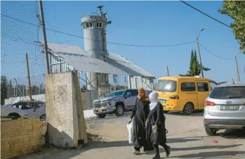  ?? MAHMOUD ILLEAN/AP ?? Palestinia­ns pass an Israeli military guard tower that has two robotic guns and surveillan­ce cameras on Oct. 6 at the Al-Aroub refugee camp. The robotic weapons can fire tear gas, stun grenades and sponge-tipped bullets.