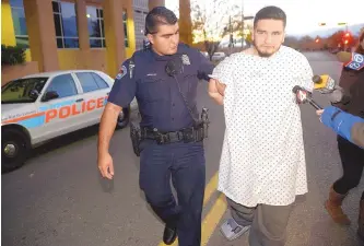  ?? ADOLPHE PIERRE-LOUIS/JOURNAL ?? Albuquerqu­e police officer Honorio Alba escorts Jacob Jaramillo, 23, to the Metropolit­an Detention Center on Sunday evening shortly after he was released from the hospital following an overnight crash that left three people dead. Police say that...