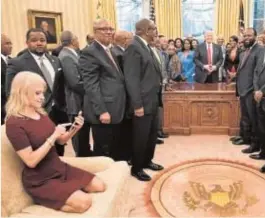  ?? AFP ?? La consejera Kellyanne Conway consulta su teléfono mientras Trump preside una reunión en el Despacho Oval