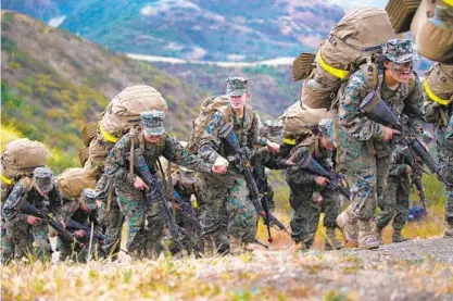  ?? NELVIN C. CEPEDA U-T PHOTOS ?? Three female Marine recruits hold hands Thursday as they crest over the final hill at the end of the grueling 54-hour Crucible exercise at Camp Pendleton. Immediatel­y after in a brief ceremony, the recruits are awarded their Eagle, Globe and Anchor pins.