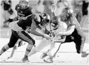  ?? JOE SKIPPER/ASSOCIATED PRESS ?? Miami’s Corn Elder, left, and Juwon Young bring down Virginia wide receiver Canaan Severin on Saturday.