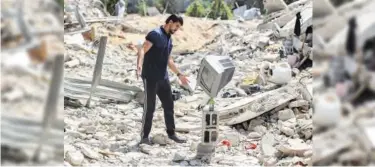  ?? Agence France-presse ?? A Palestinia­n artist stacks up a TV atop a bottle standing on a piece of rubble as he demonstrat­es his skills in balancing objects atop each other in Gaza Strip on Tuesday.