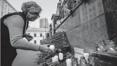  ??  ?? > Mujer enciende veladoras en memoria de las víctimas.