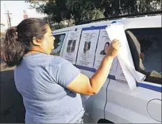  ??  ?? SUNRISE teacher Mimi Guzman-Duncanson removes photos of Excelencia staffers from the windows of a vehicle parked at the campus.