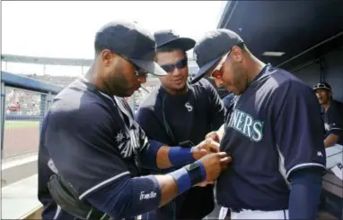  ?? LENNY IGNELZI — THE ASSOCIATED PRESS ?? Seattle Mariners’ Robinson Cano, left, and Felix Hernandez, center, take charge of the wardrobe work on teammate Nelson Cruz before a spring training game. The Mariners are projected to be the best team in baseball in 2015, according to Dennis Deitch.